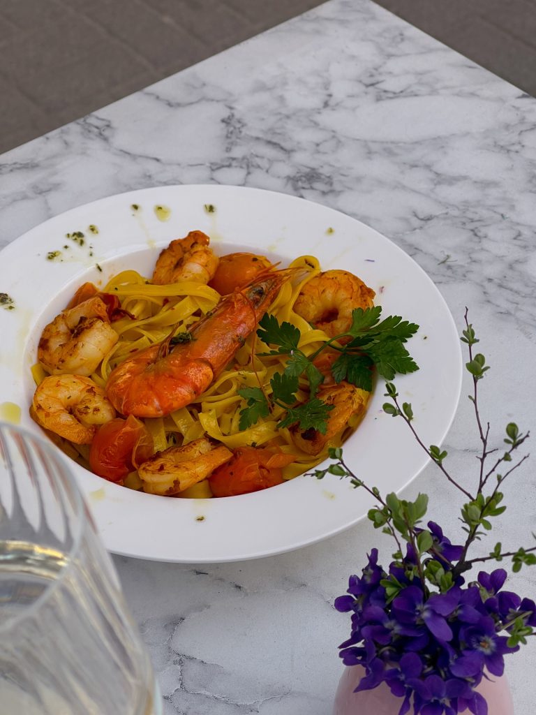 Piatto di pasta fresca con gamberoni e pomodorini servito all'aperto da Bube Restauracja i Pizza a Breslavia